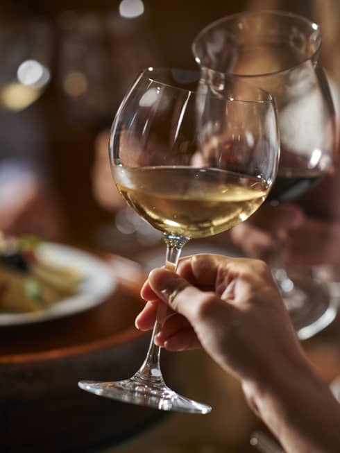 Two guests clink their wine glasses together at dinner