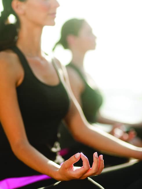 Two women sitting in a yoga pose.