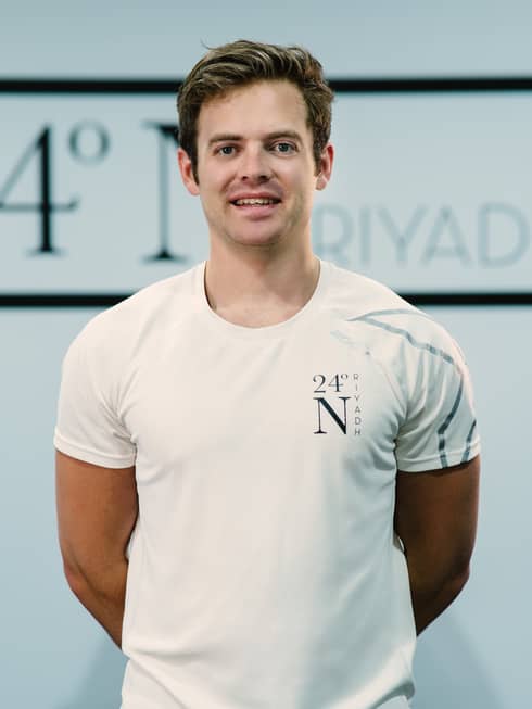 Max Whiteside standing with his arms behind his back wearing a white company shirt.