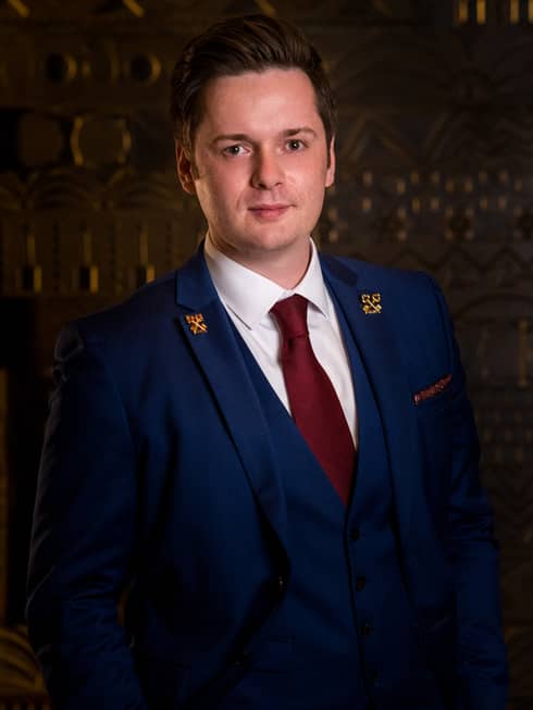 Zalan Schuster wears a navy blue three-piece suite with white shirt, red tie and gold Les Clefs d?Or pins on his lapel