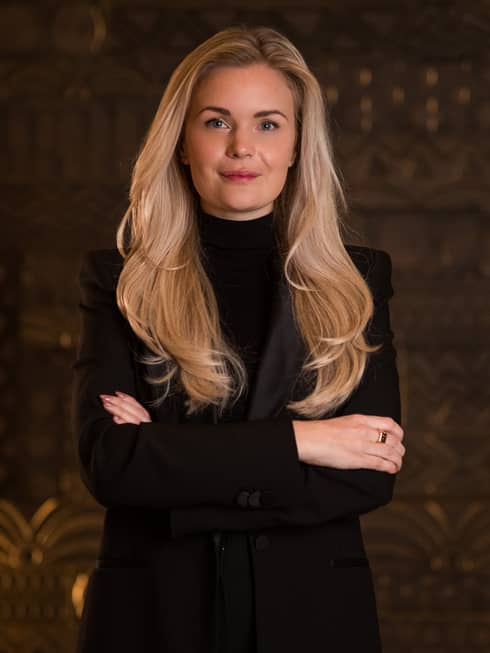 Portrait of Guest Experience Manager Johanna Fagerberg, a blonde woman wearing a black suit standing with her arms crossed