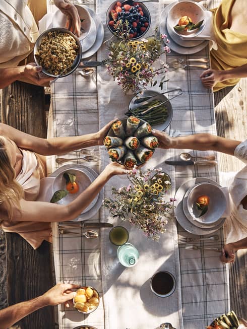 Guests sitting around a table and passing bowls of food.