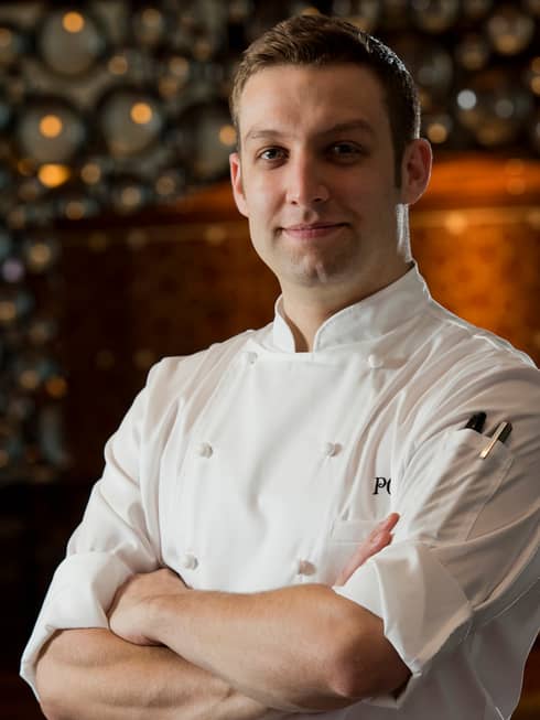 Portrait photo of Executive Pastry Chef Pierre Chambon in white uniform, smiling with arms crossed