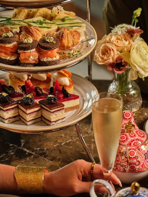 A three-tiered display of sweets beside a vase of flowers