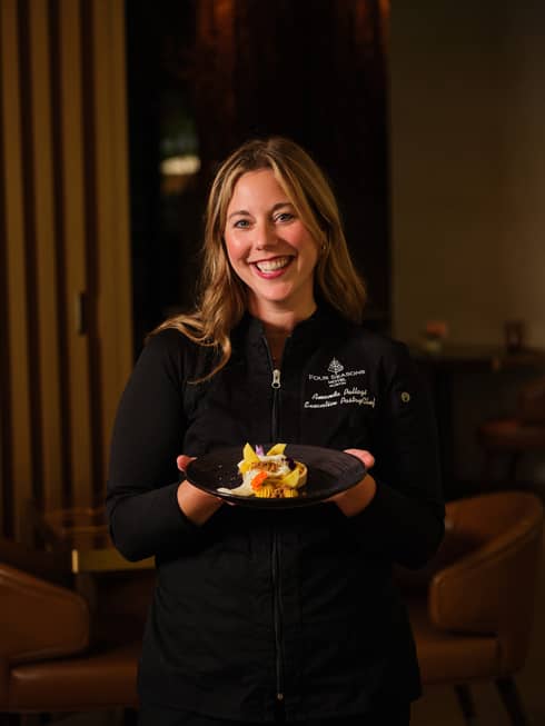 Person wearing a Four Seasons jacket and holding a plate of food