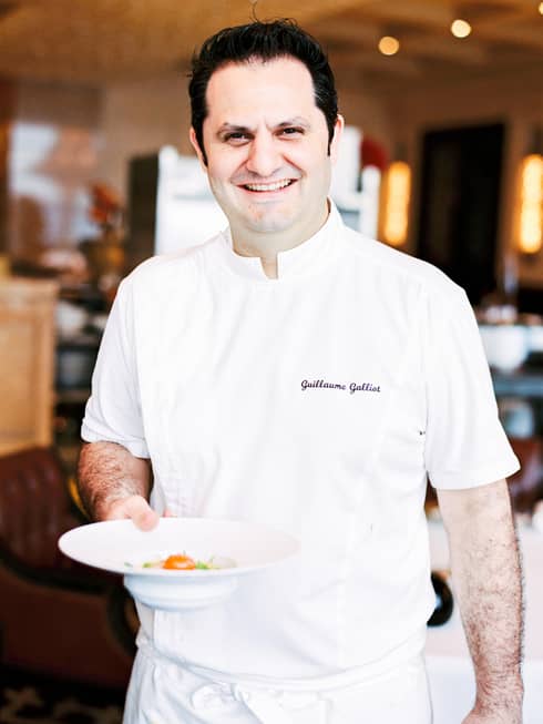 Portrait photo of Chef de Cuisine Guillaume Galliot holding plate