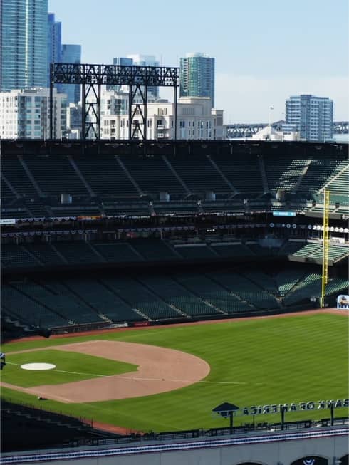 View of a baseball field, empty stands and city skyline behind