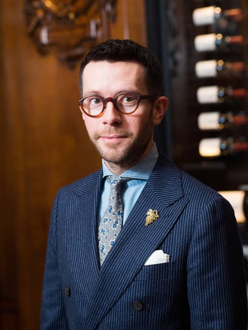 Portrait photo of La Dame de Pic London's Director of Wine, Jan Konetzki, in blue suit and brown-rimmed glasses