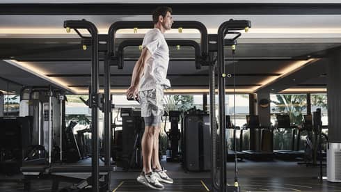 Man in athletic wear jumping vertically beside workout equipment in gym