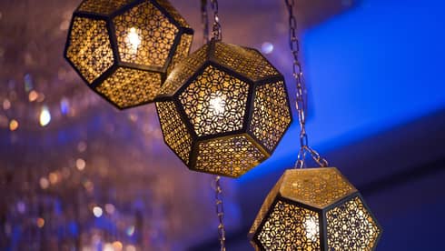 Several golden octagonal lights hanging from the ceiling, with a blue illuminated background.