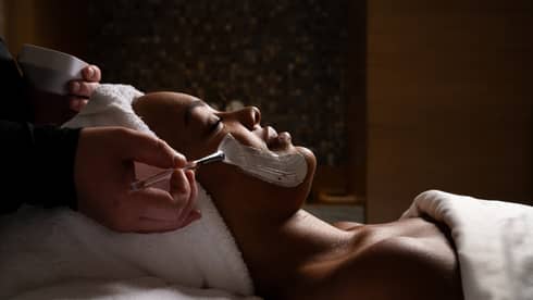 Guest laying on a massage table while getting a facial.