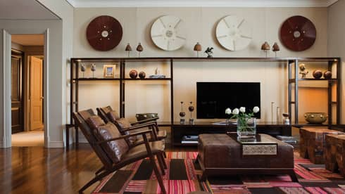 Modern brown leather armchairs and large ottoman with fresh flowers, modern and wood Argentine-inspired art