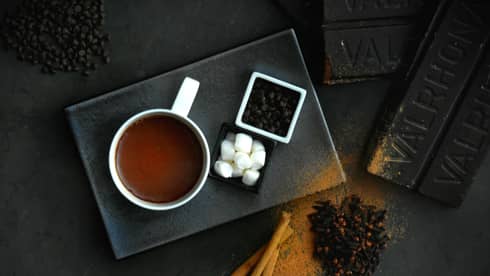 Hot chocolate, marshmallows and other ingredients on a black plate.