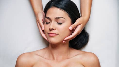 Woman with eyes closed as hands massage her face