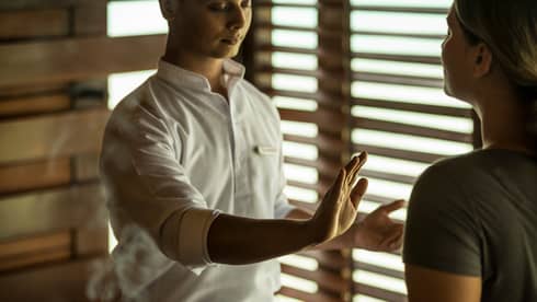 Reiki healer with eyes closed holds hand over woman's body