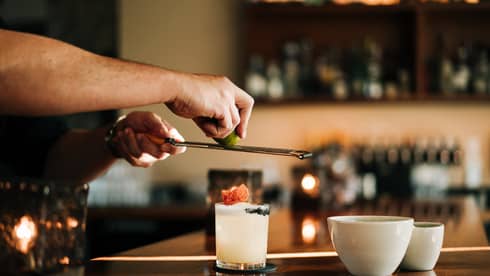 A person standing at a bar and making a drink in a glass