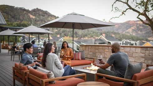 A group of people sitting outside with glasses of wine.