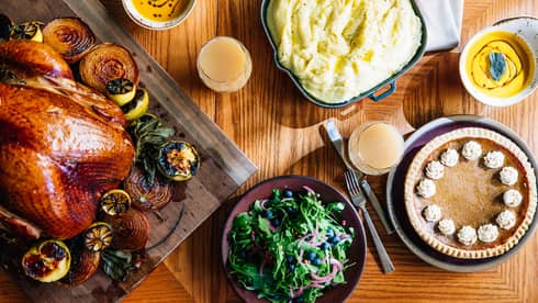 An aerial shot of a thanksgiving dinner including a roasted turkey with vegetables, mashed potatoes, salad and pumpkin pie
