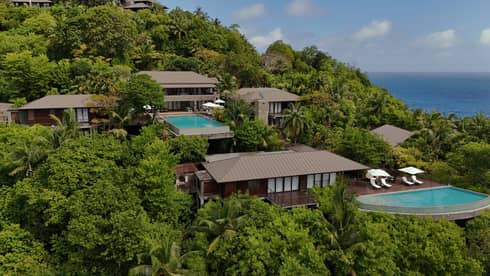Aerial view of a large private residence with pool nestled on lush ocean-view hillside