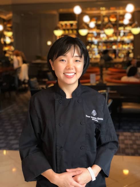 Headshot of Executive Pastry Chef Erica Lee with dimly-lit restaurant in the background.