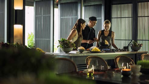 Chef, two women look at pan on kitchen range at Hoi An Cooking Academy 