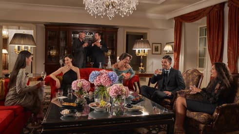 People mingle in an elegant living room with crystal chandelier