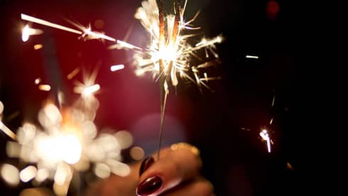 Hands holding a lit sparkler.