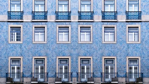 A blue tiled wall with many windows and balconies.