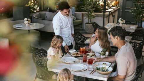 Family of four dines at a table on a restaurant terrace