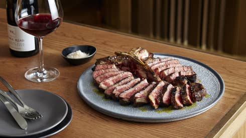 Slices of Dry-Aged T-Bone Steak arranged in circle on blue plate