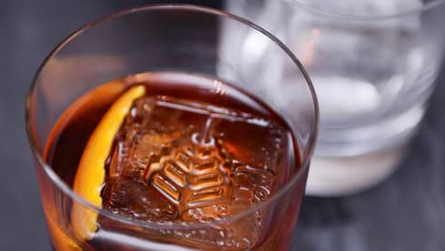 A Four Seasons branded ice cube floats alongside an orange peel in barrel-aged Negroni