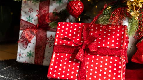 Red and white presents wrapped under a Christmas tree