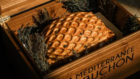 Beef Wellington plated in a wooden box and surrounded by greenery