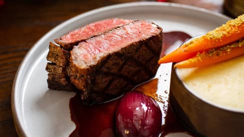 Steak with a red sauce on a grey plate.