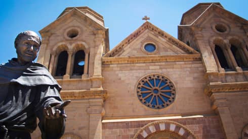 Statue of monk in front of stone New Mexico cathedral church