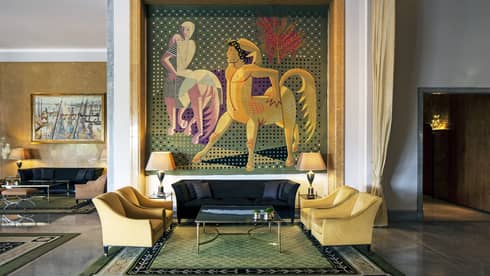 Almada Negreiros Lounge yellow armchairs below large handmade tapestry depicting centaurs