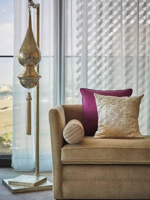 Moroccan lamp, sofa with accent pillows in front of window with white curtains