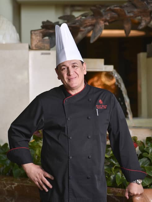 Chef from Four Seasons Hotel Doha stands near a fired oven