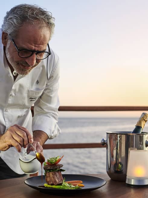 Chef Sebastiano Spriveri places finishing touches on dish outdoors with Red Sea in background