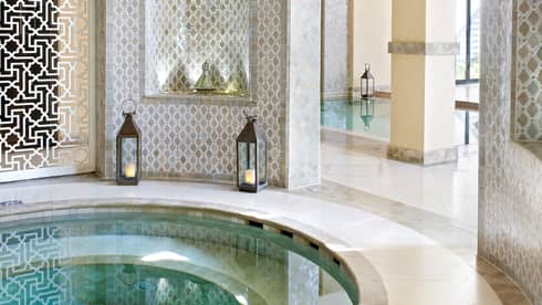 Small round whirlpool tub surrounded by decorative white detail wall, lanterns