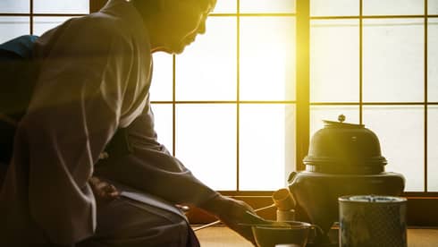 Woman in traditional Japanese kimono serves tea for herself