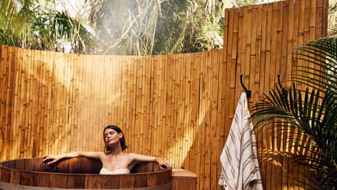 A woman in a wooden tub outside.