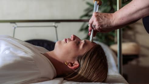 A woman receiving a sound healing treatment at a spa.
