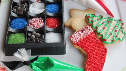 Stocking, christmas free and star-shaped Sugar cookies with sprinkles, icing and chocolate chips next to them 