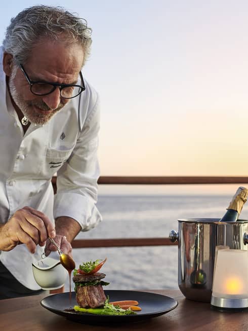 Chef Sebastiano Spriveri places finishing touches on dish outdoors with Red Sea in background