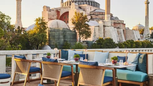 Terrace with outdoor table and blue cushioned chairs and the Blue Mosque in the background