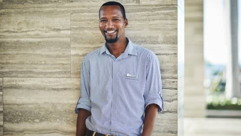 Portrait image of smiling personal assistant standing against marble wall
