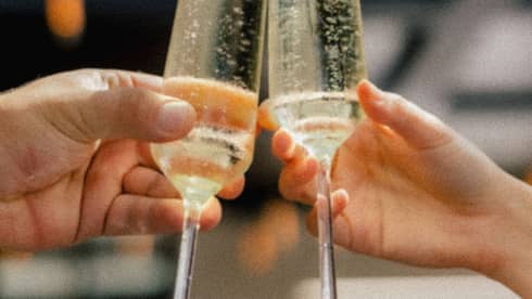 Two hands holding glasses of sparkling wine clink