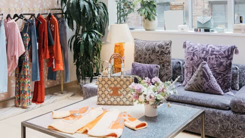 Clothes on a table and hanging near large windows.