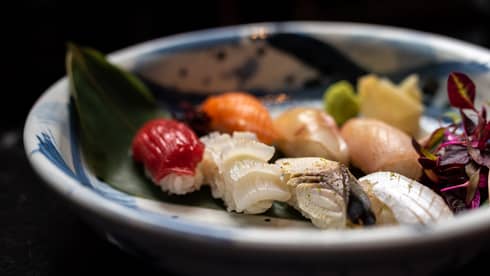 Colourful nigiri selection on palm leaf in blue-and-white bowl